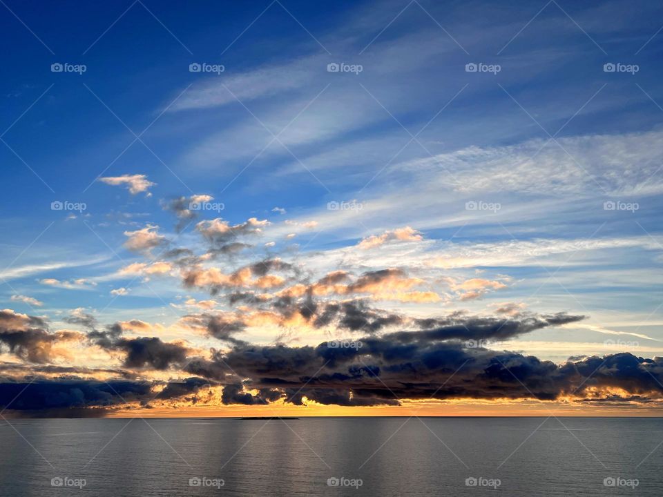 Amazing sunset view over the Baltic Sea archipelago with clouds reflection in the still mirror smooth water surface