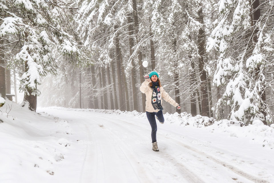 Woman playing with snowball on street