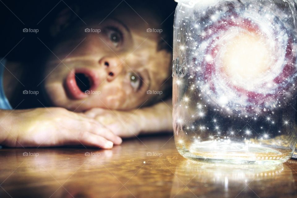 Shocked boy looking at galaxy in the jar
