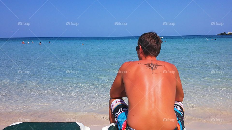 Young man back in the sun looking at the blue sea of ​​jamaica