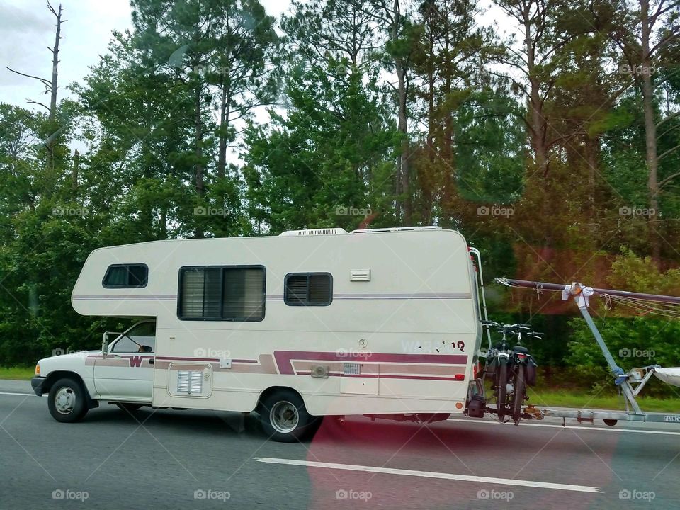 Summer activities in USA. Road trip in an older driveable mobile home. Camper is seen driving down highway!