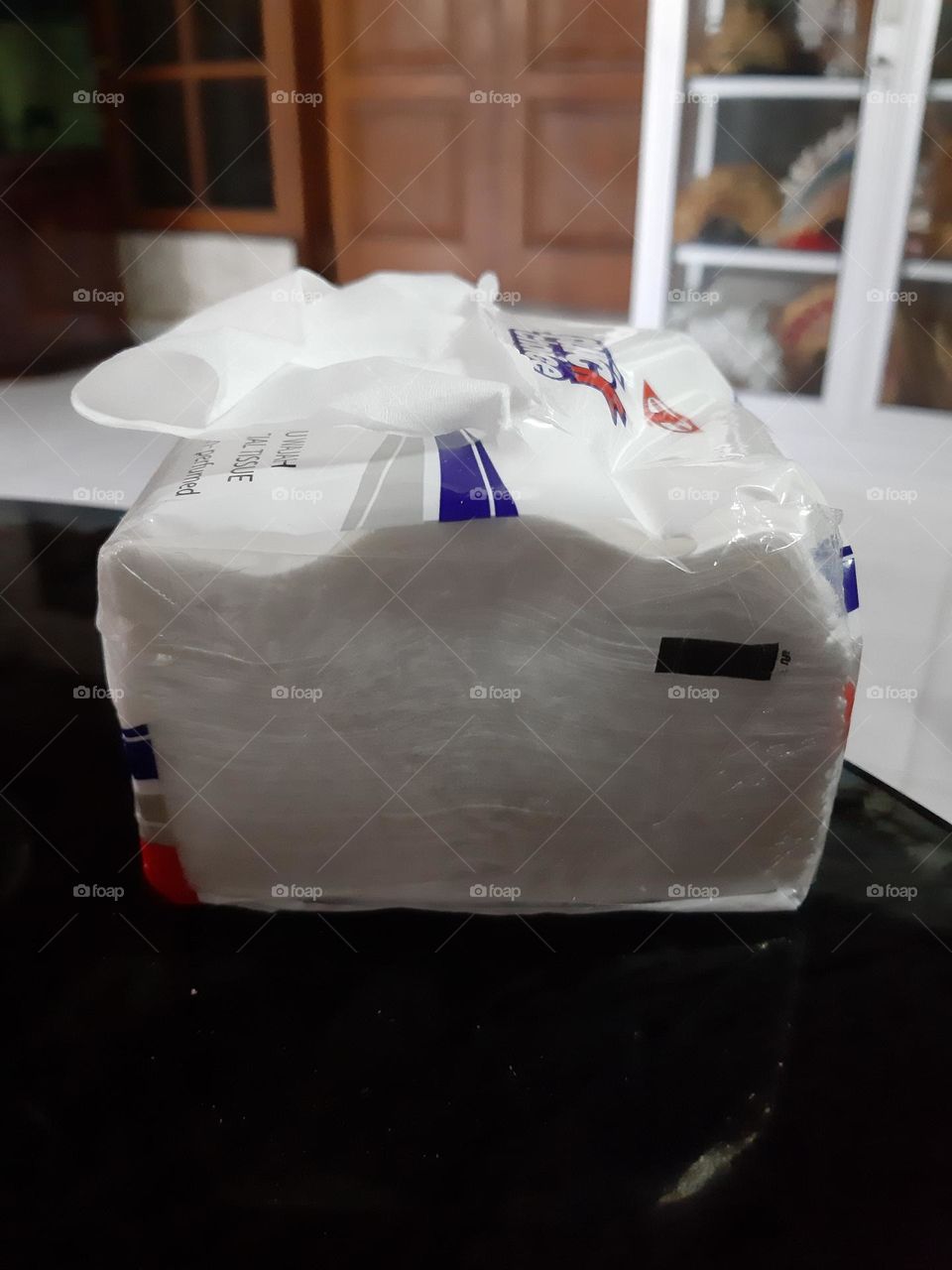 a box of white tissue paper on the black table. Tissue is used to clean the dirty stuff.