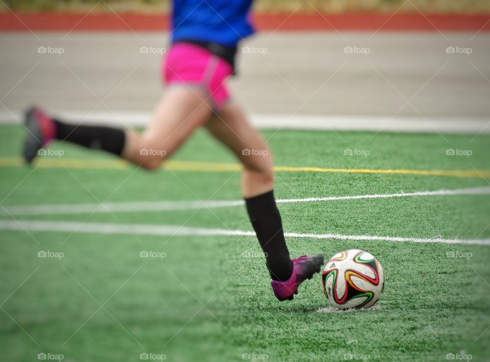 Legs Kicking A Soccer Ball. Girl Playing Youth Soccer
