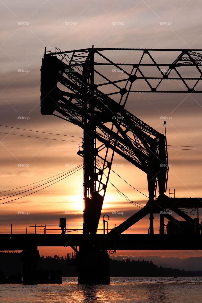 A metal railroad bridge is shadowed by the setting sun in Steilacoom, Washington 