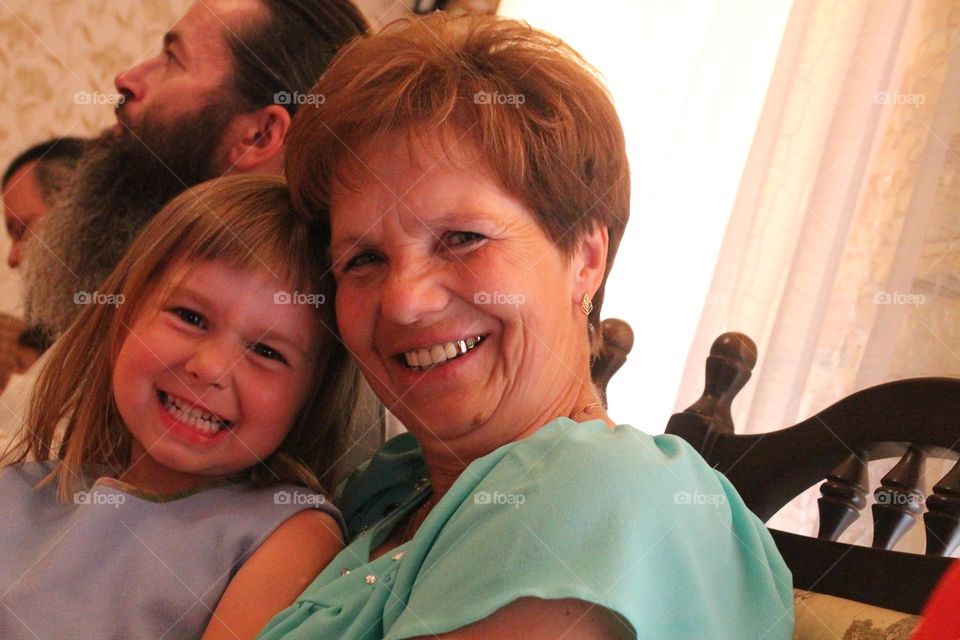 A happy little girl is smiling in a photo with her grandmother