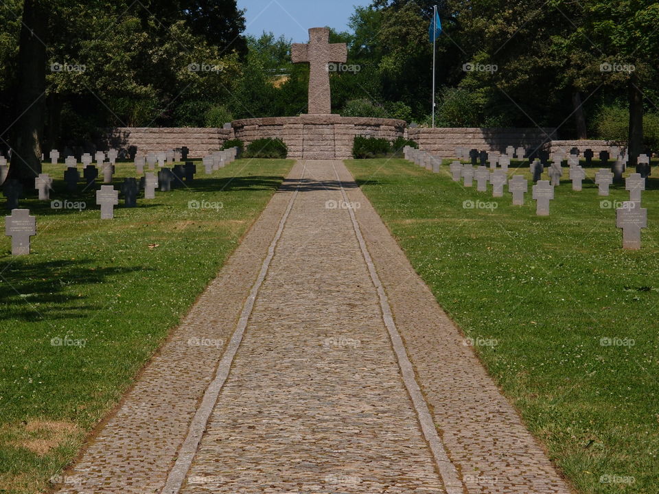 A brick walkway through a German Cemetery in Luxembourg where Germans who lost their lives during The Battle of the Bulge are buried under beautiful crosses on a summer day. 