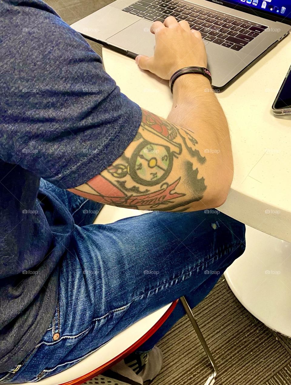 Man using computer with tattoos on his arm