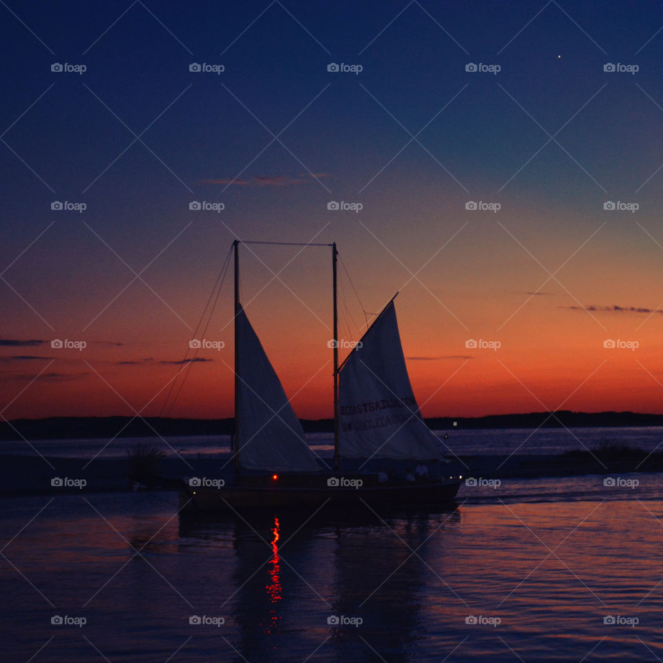 Silhouette of sailboat on lake at sunset