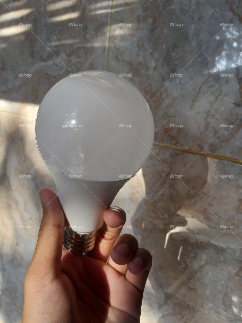 a human left hand holds a big white bulb.