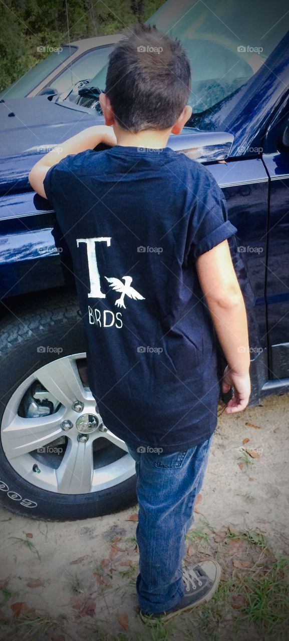 Rear view of a boy standing near car