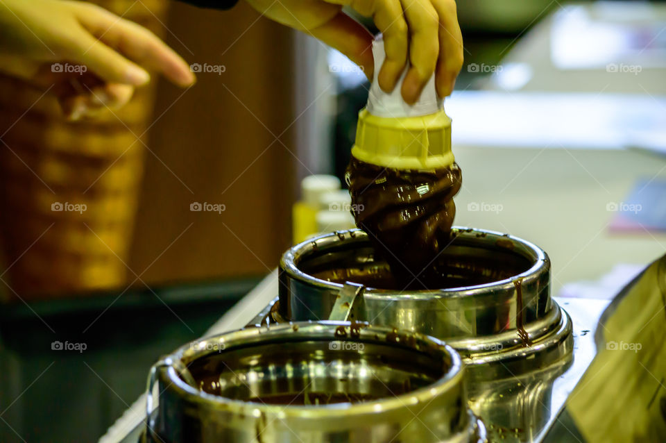 Decadent dark Chocolate Dip hands holding ice cream cone coated with a rich chocolate sauce 