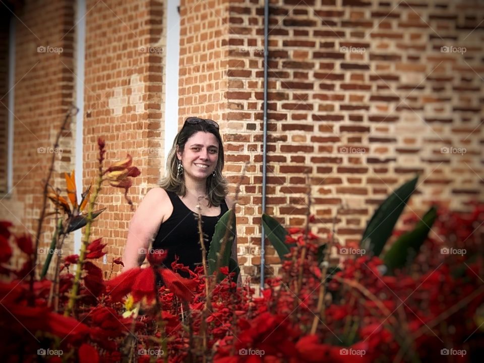 Lovely lady in a garden full of red flowers, and vintage buildings. Romance may be in the air...