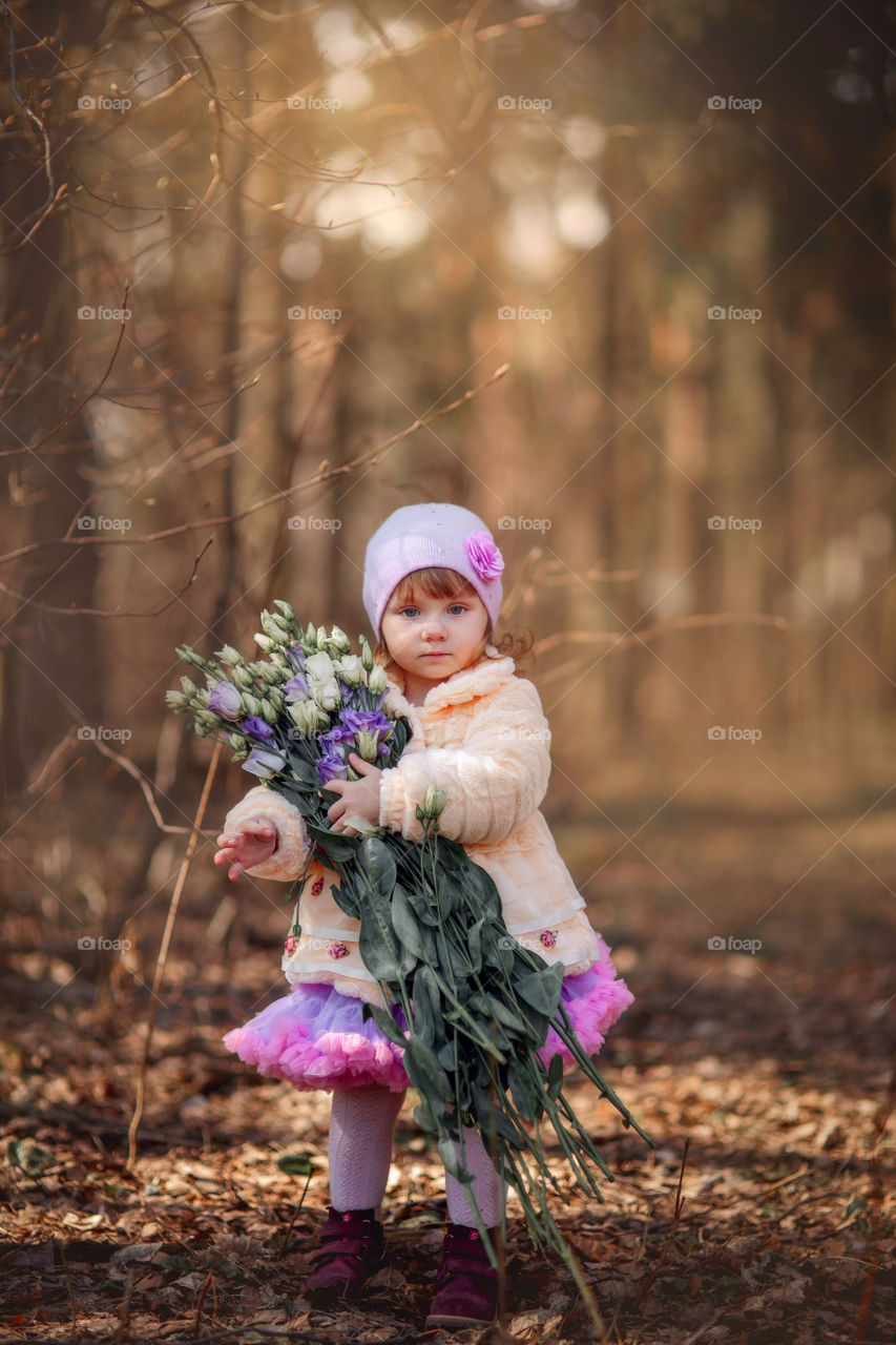 Little girl with bouquet of eustoma  flowers in spring park