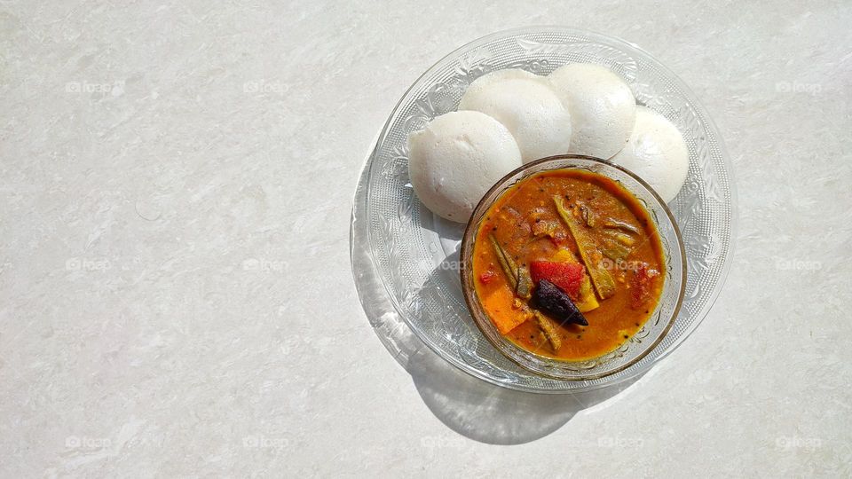 Idli and sambar, sambar a vegetable curry medium spicy, Idli is a pure white colour fluffy steamed batter consisting of fermented black lentils (de-husked) and rice