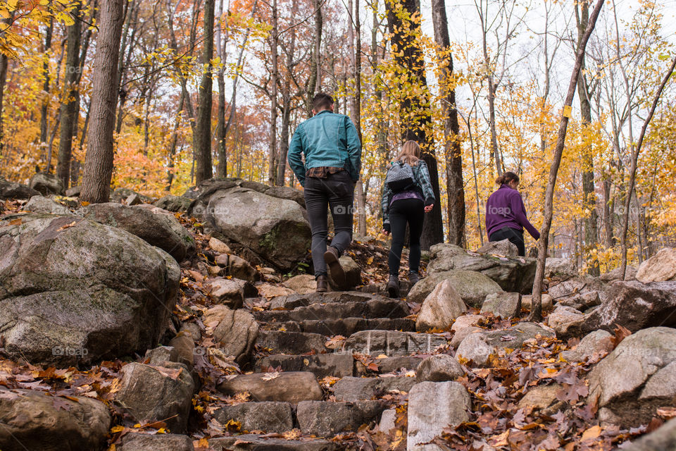 Hikers walk up the stone stairs during autumn in a reservation