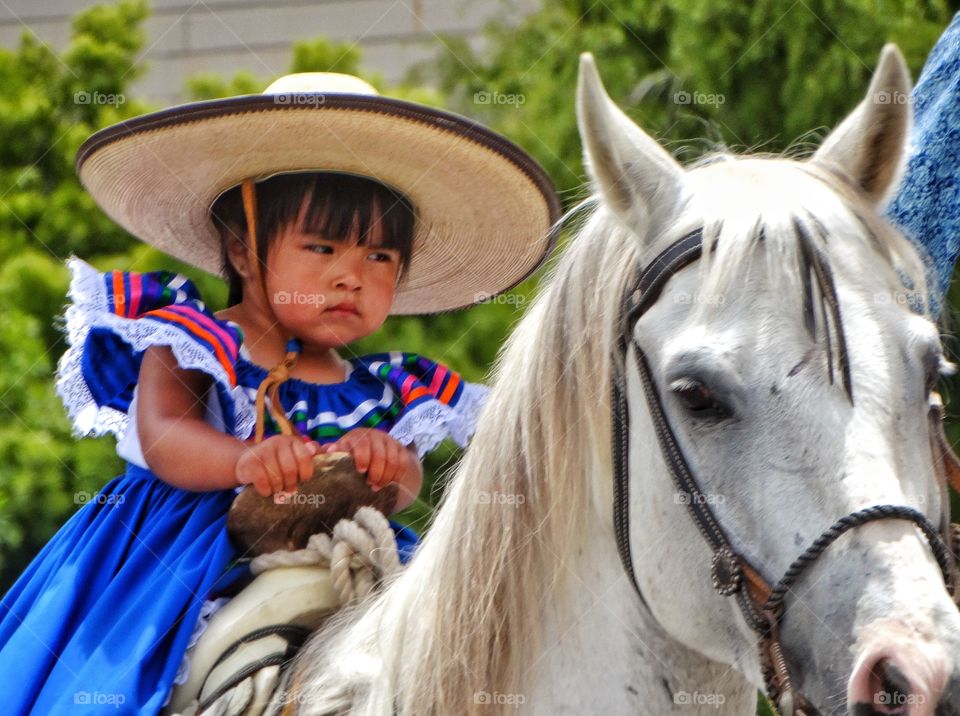 Girl On A White Horse. Young Mexican Girl In A Colorful Dress Riding A White Stallion
