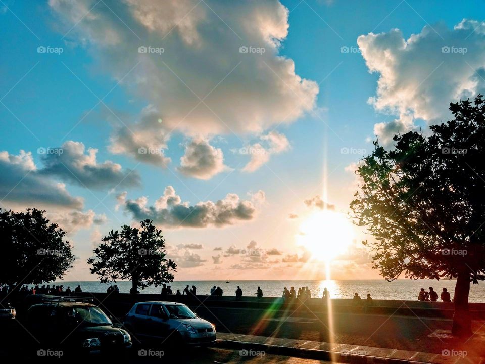 On a summer evening at Marine drive spotted amalgamation of Nature and fast forward life of 21st century. People chilling with rainbow colours in piercing Sun rays with cool Sea wind, diverse sky decorated with clouds on one side and traffical music.