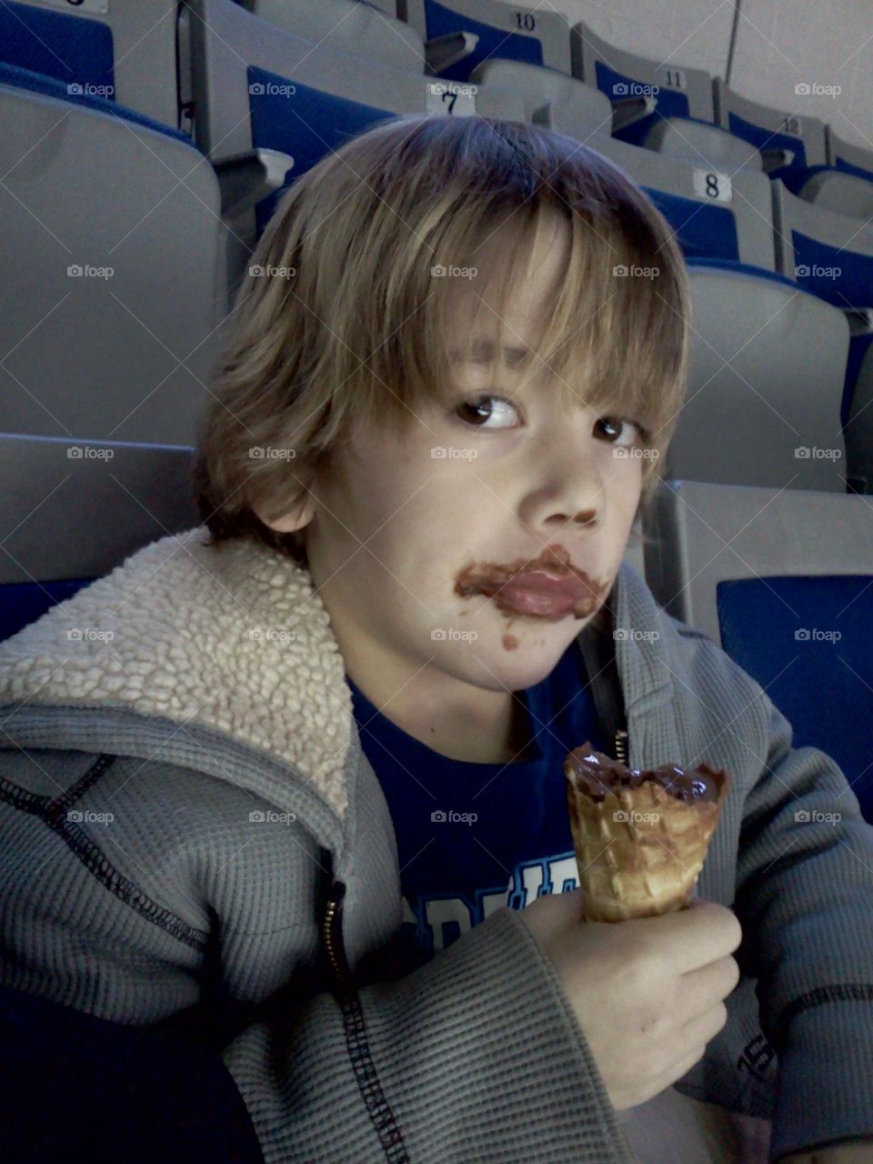 Boy eating chocolate ice cream cone with messy face
