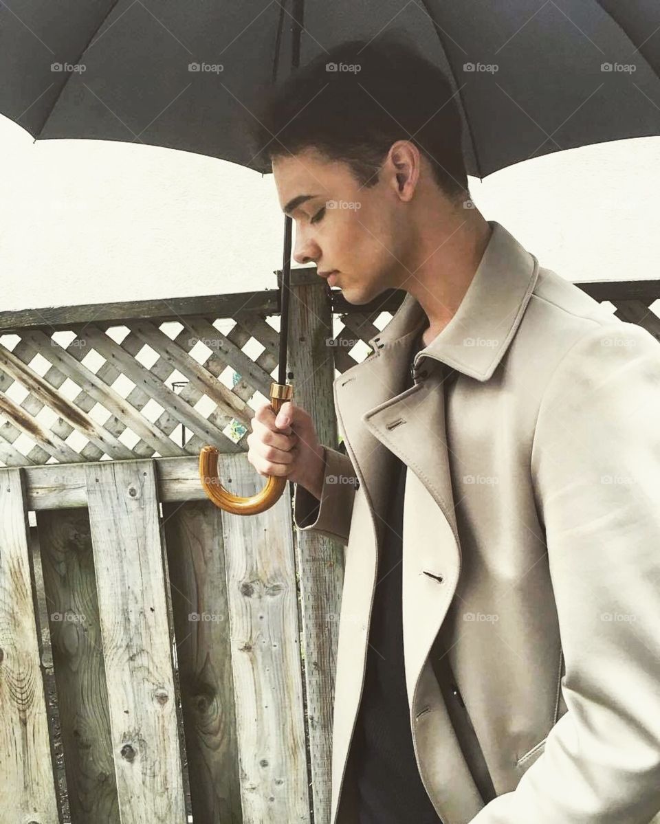 Man's profile with an umbrella, lightly smiling 