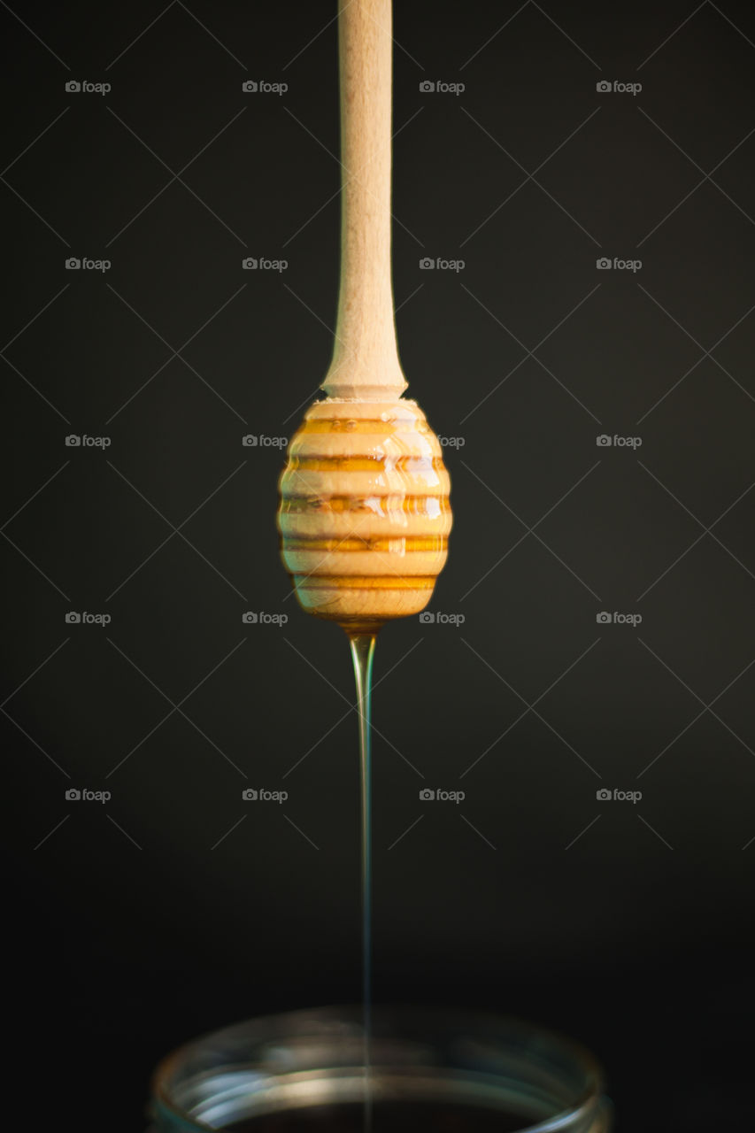 Honey and honey spoon on a light background. Sweet honey in the jar, place for text.