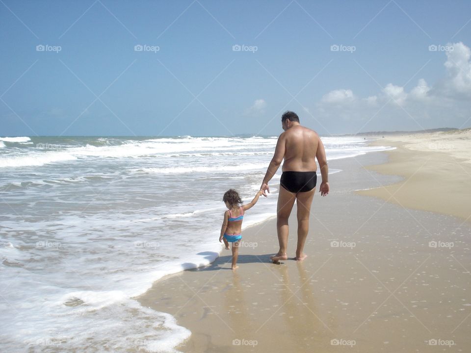 Father and daughter walking on the beach in summer