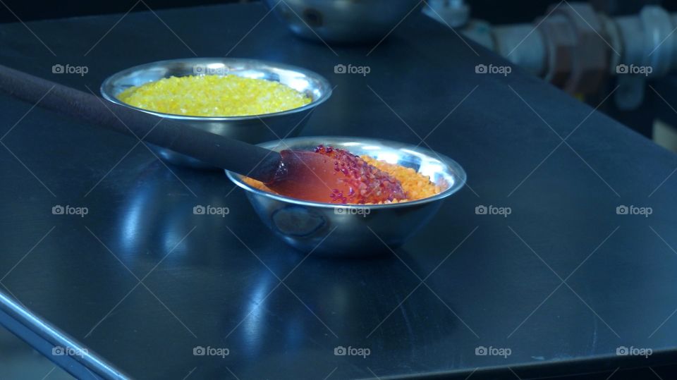 Person dipping hot glass into bowl with orange glass fragments to make blown glass ornament