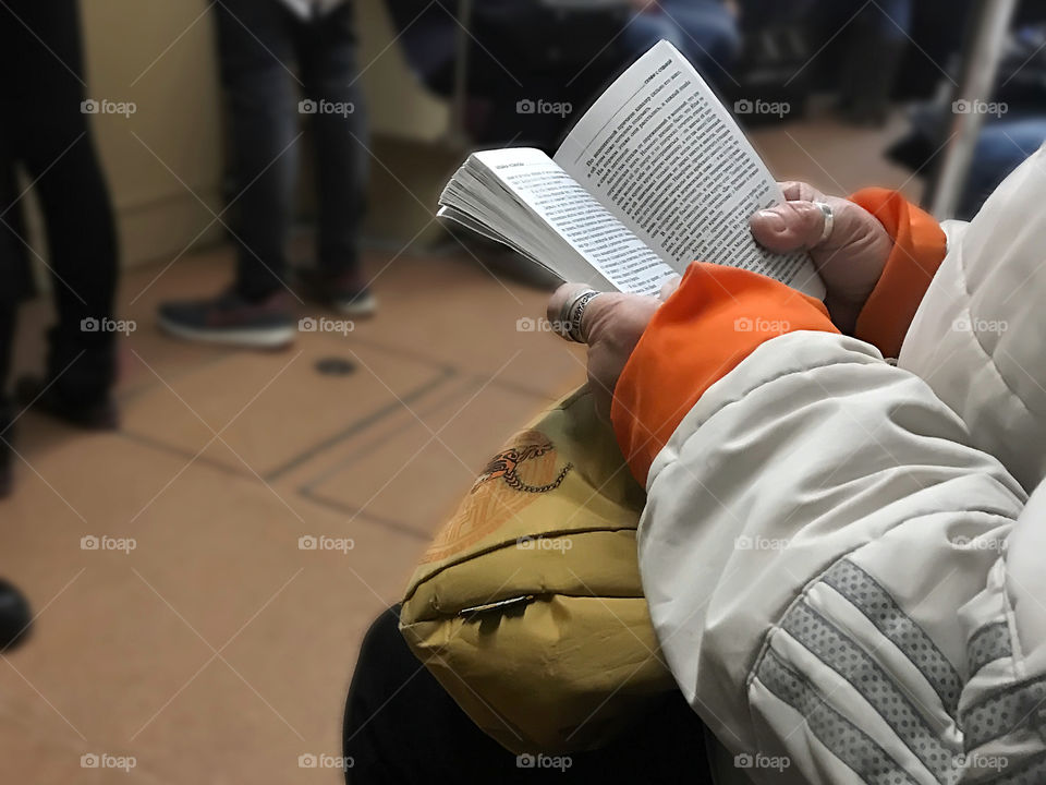 Senior woman reading a book in subway train 