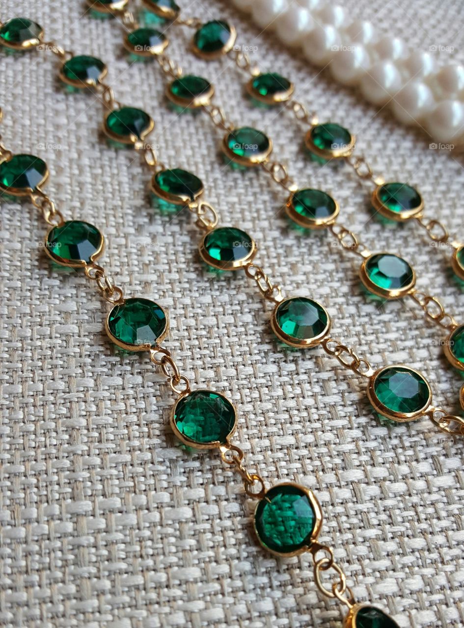Close-up of a gold necklace with emerald green bezel cut crystals
