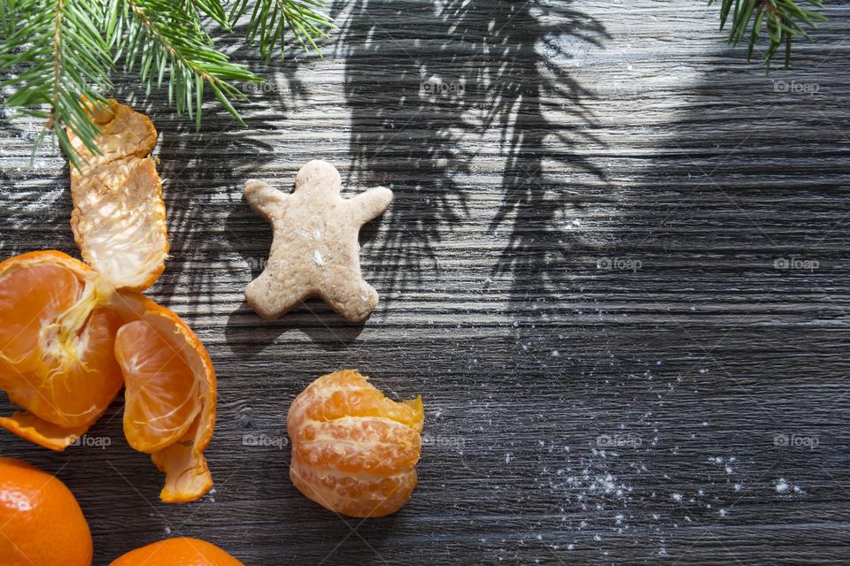 Cooking Christmas gingerbread cookies on a wooden table with tangerines and green Christmas trees.