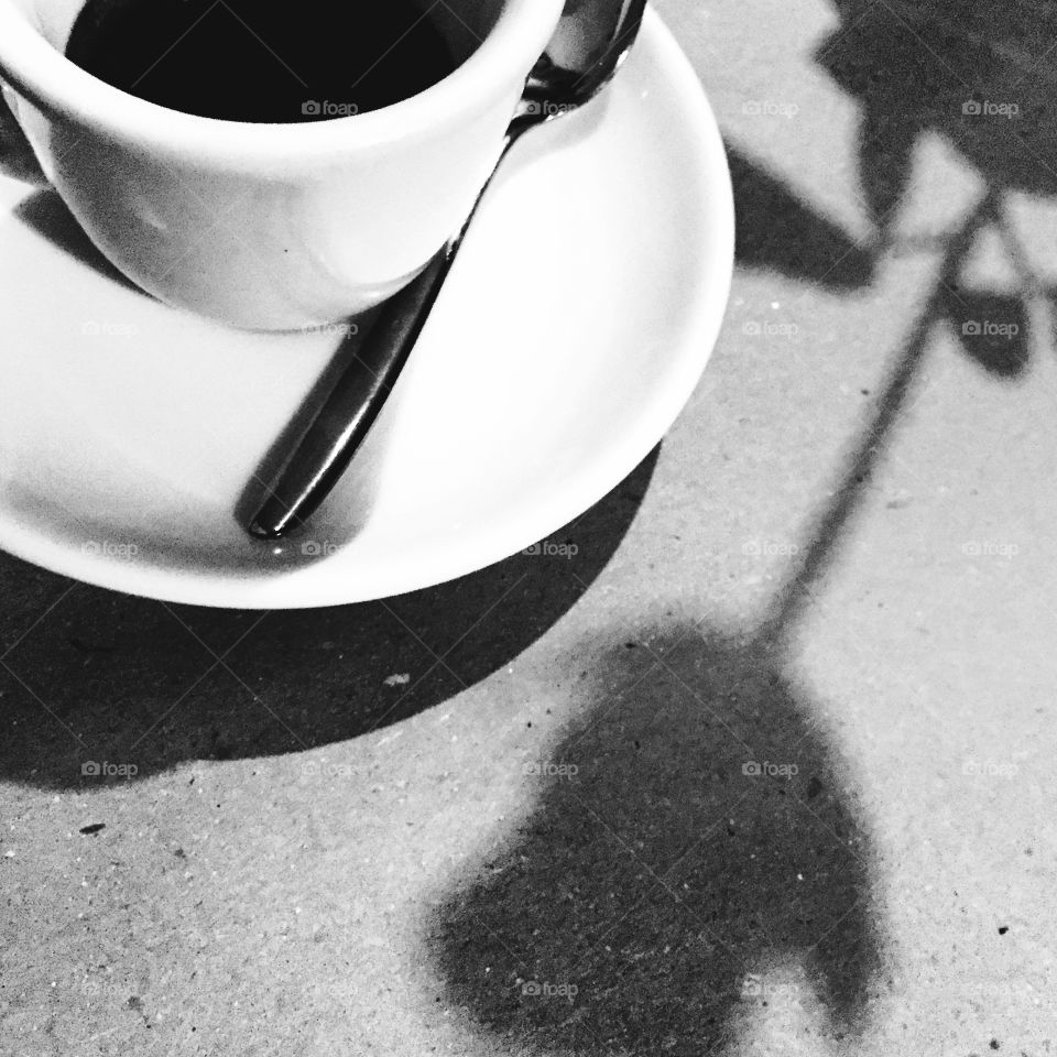 Cup of coffee and shadow of flower