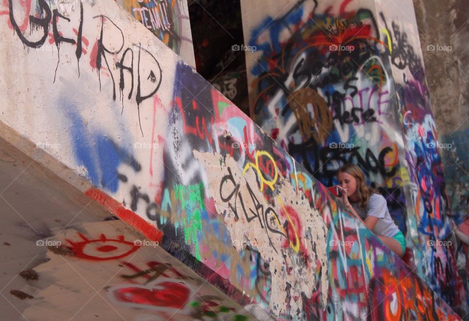 Young woman crouching on building with graffiti