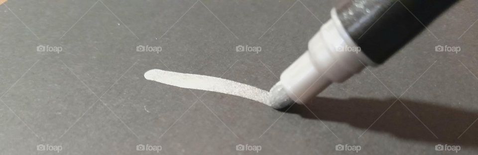 a silvery inky marker drawing on plain back sketching paper, shining out to the world.