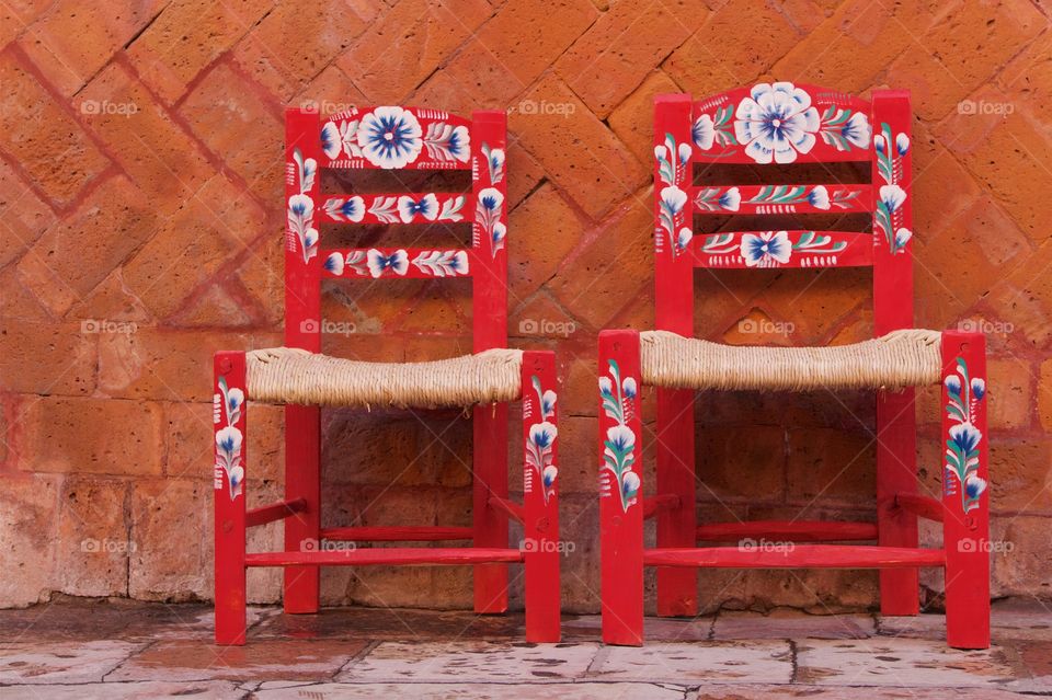 Two colorful red handcrafted straw chairs spotted on the sidewalk in San Miguel de Allende, Mexico,