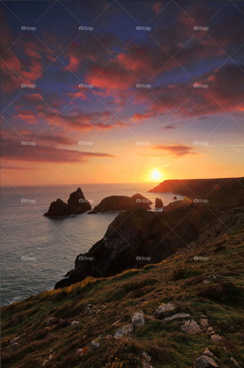 Kynance Cove Sunset. A cliff top sunset of a wide Ocean and several small islands in silhouette.