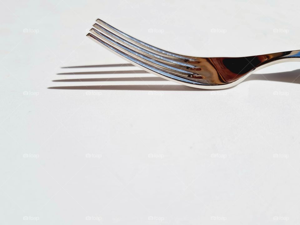 fork on white background and its shadow