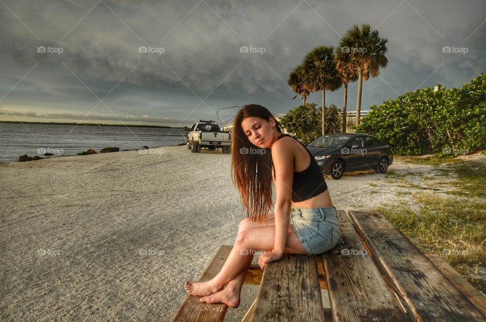 Sad woman sitting on wooden table at beach