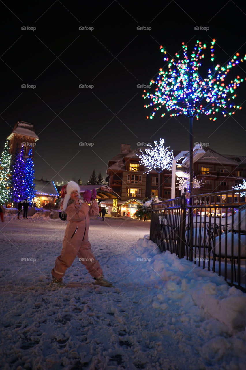 Girl in santa hat standing in front of illuminated building