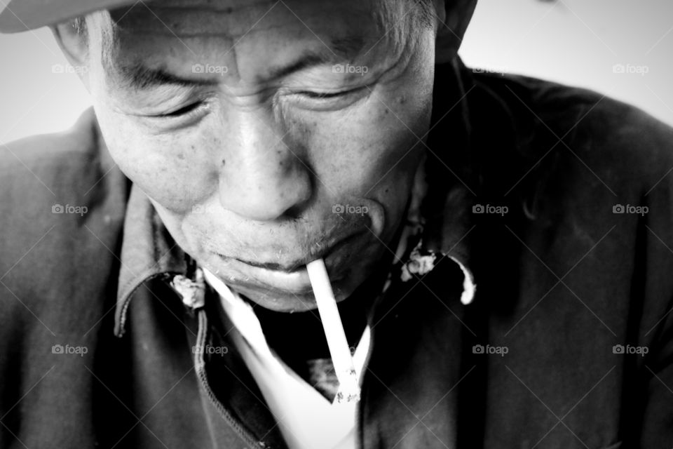 Age. An old man who is lighting his cigarette 