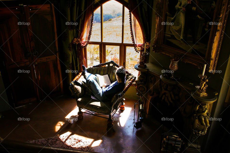 2019 a year of enjoying little things in life. Image of woman at a window reading a book and a cup of coffee on the floor