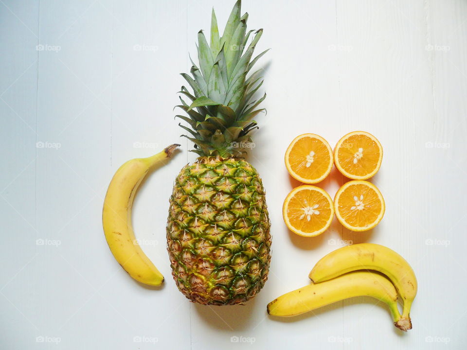 pineapple, sliced ​​orange and bananas on a white background