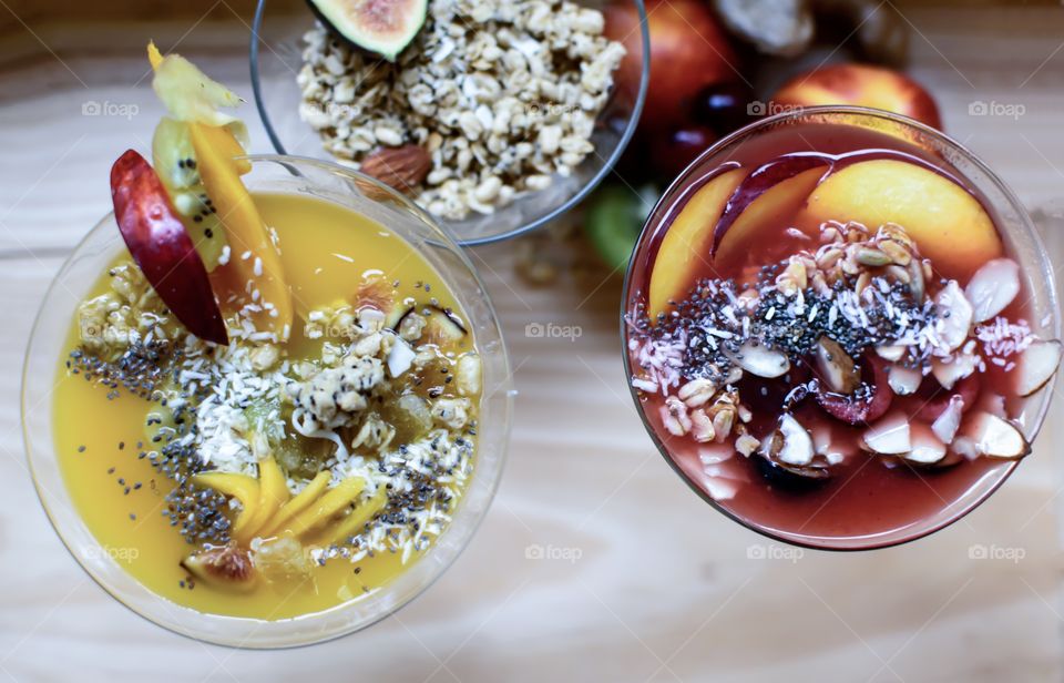 Variety of Beautiful colorful Smoothie bowls with fruits, nuts, coconut, chia seeds, oatmeal and sunflower seeds from elevated view garnished with fresh healthy ingredients part of a series