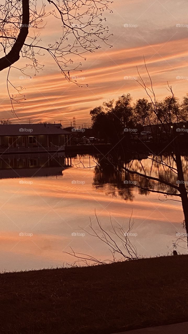 As evening progresses sunset twilight colors are appearing streaks of colors visible as reflections on lake water. 