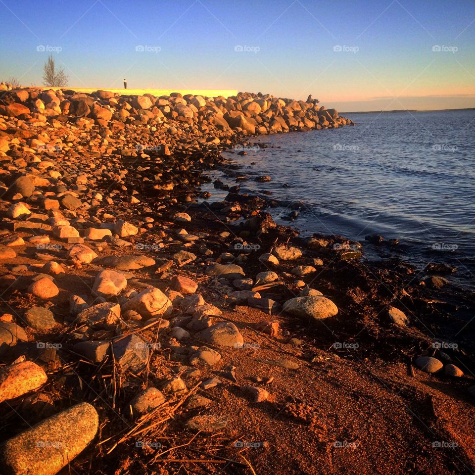 Sunset on  beach  shining on  rocks 
