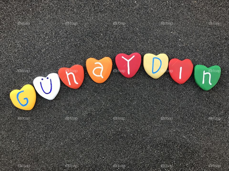 Günaydın, turkish good morning with colored heart stones over black volcanic sand