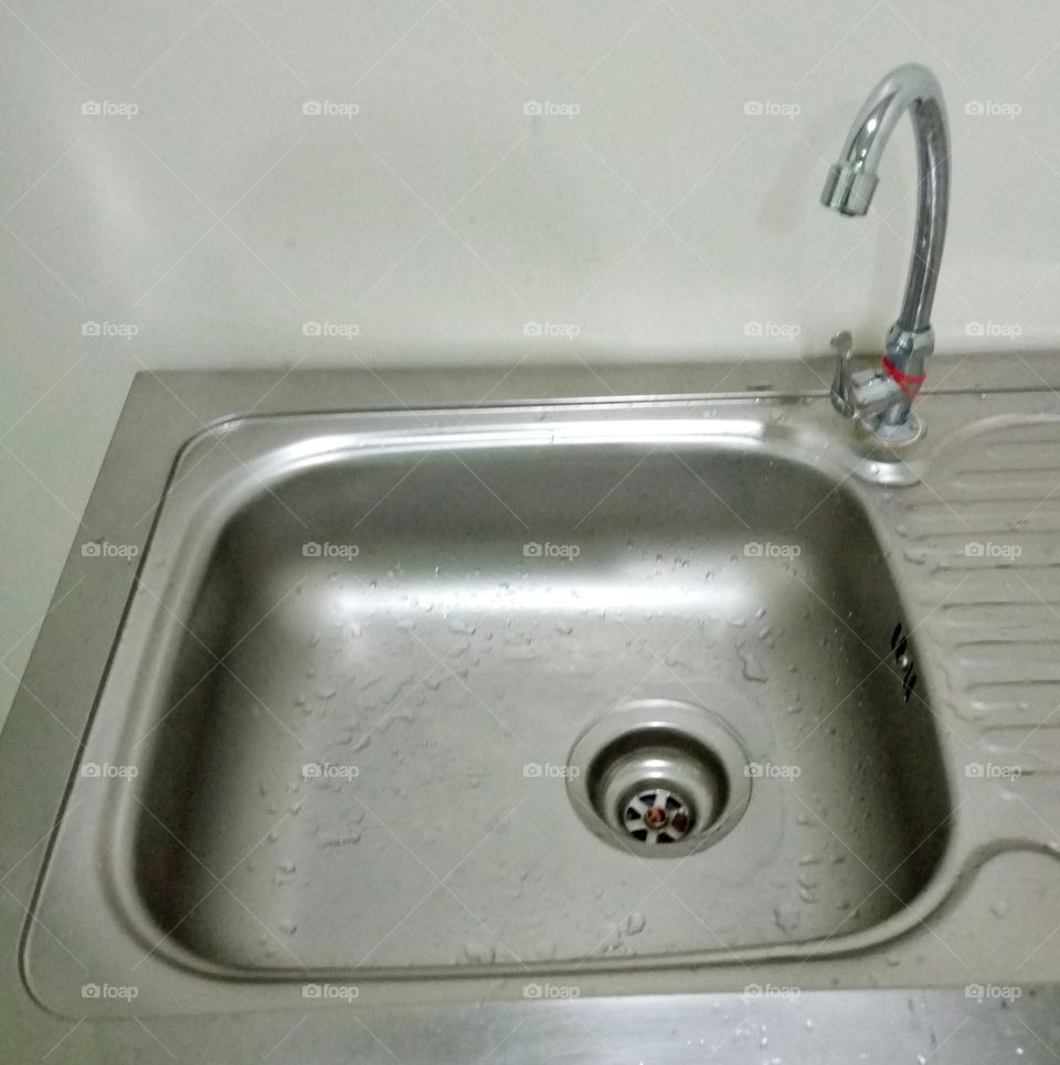 The sink is made of stainless steel with water.
