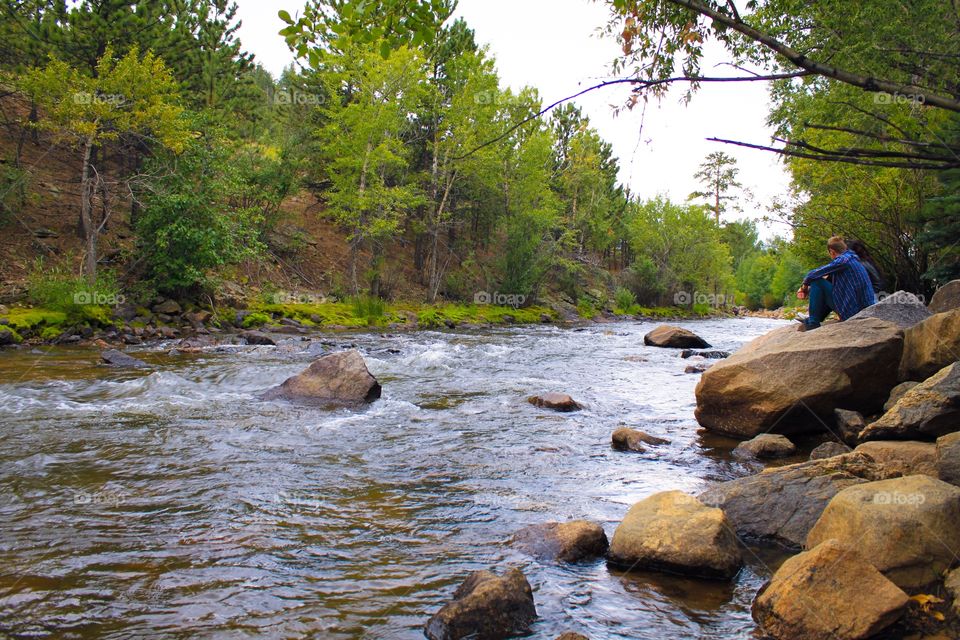 Couple sitting on rock at river side