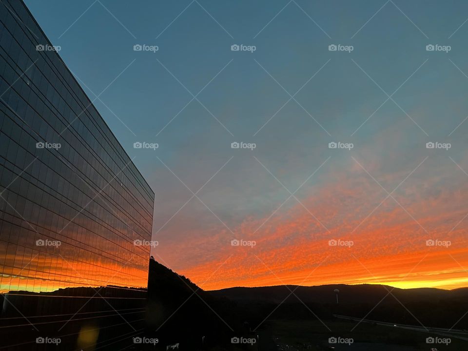 Mirrored building with reflection of beautiful orange and blue sunset