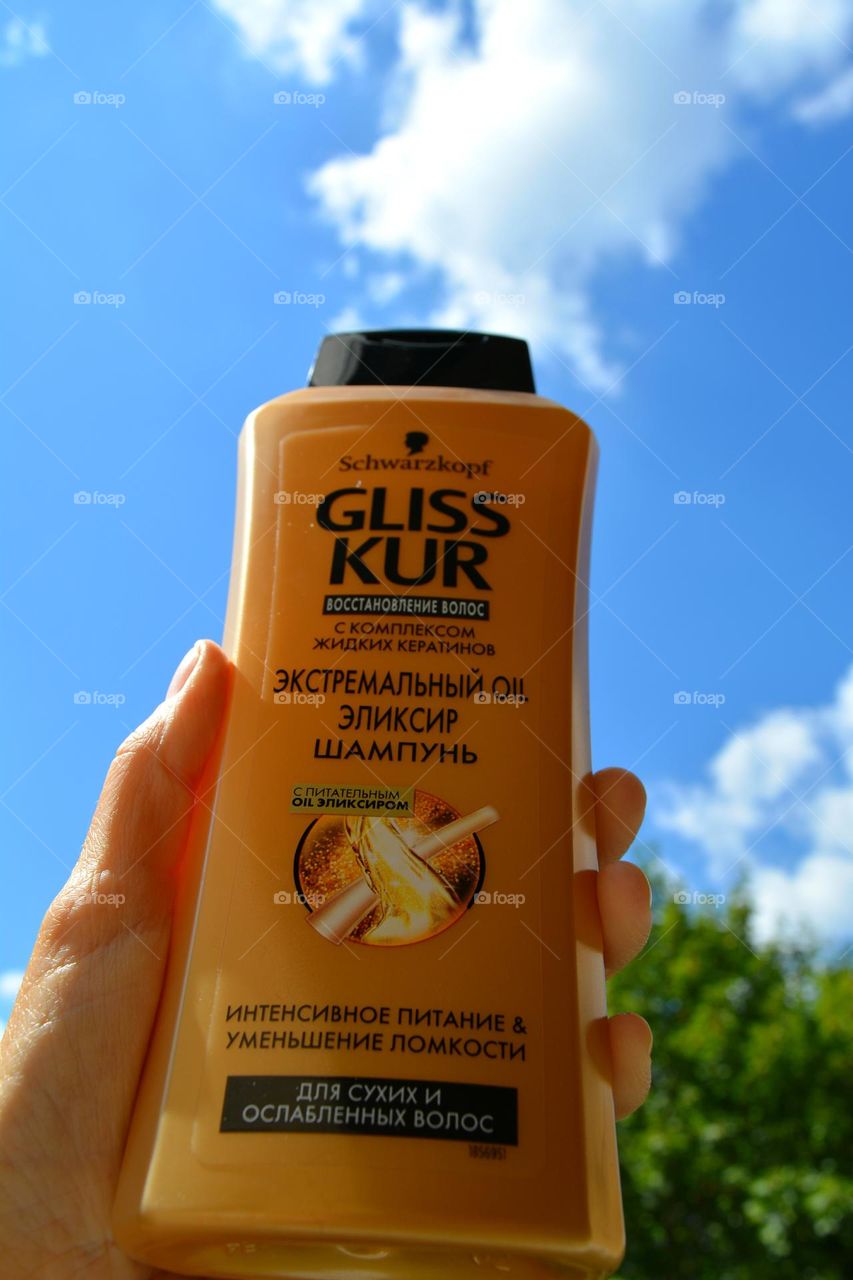 shampoo Gliss Kur in the hand blue sky background