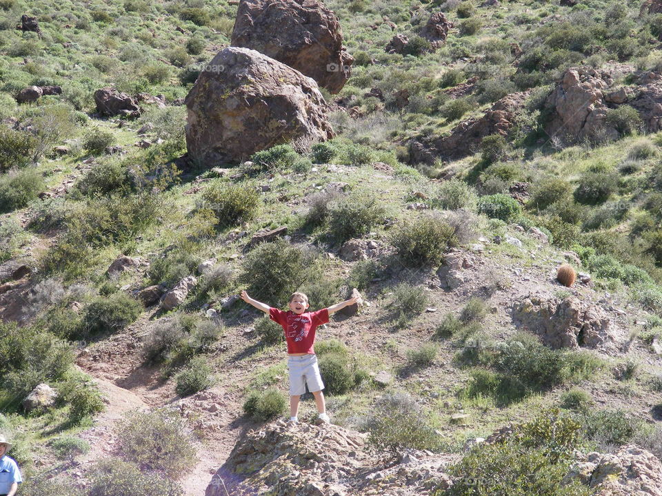 This boy is standing on the side of a desert valley mountain.
