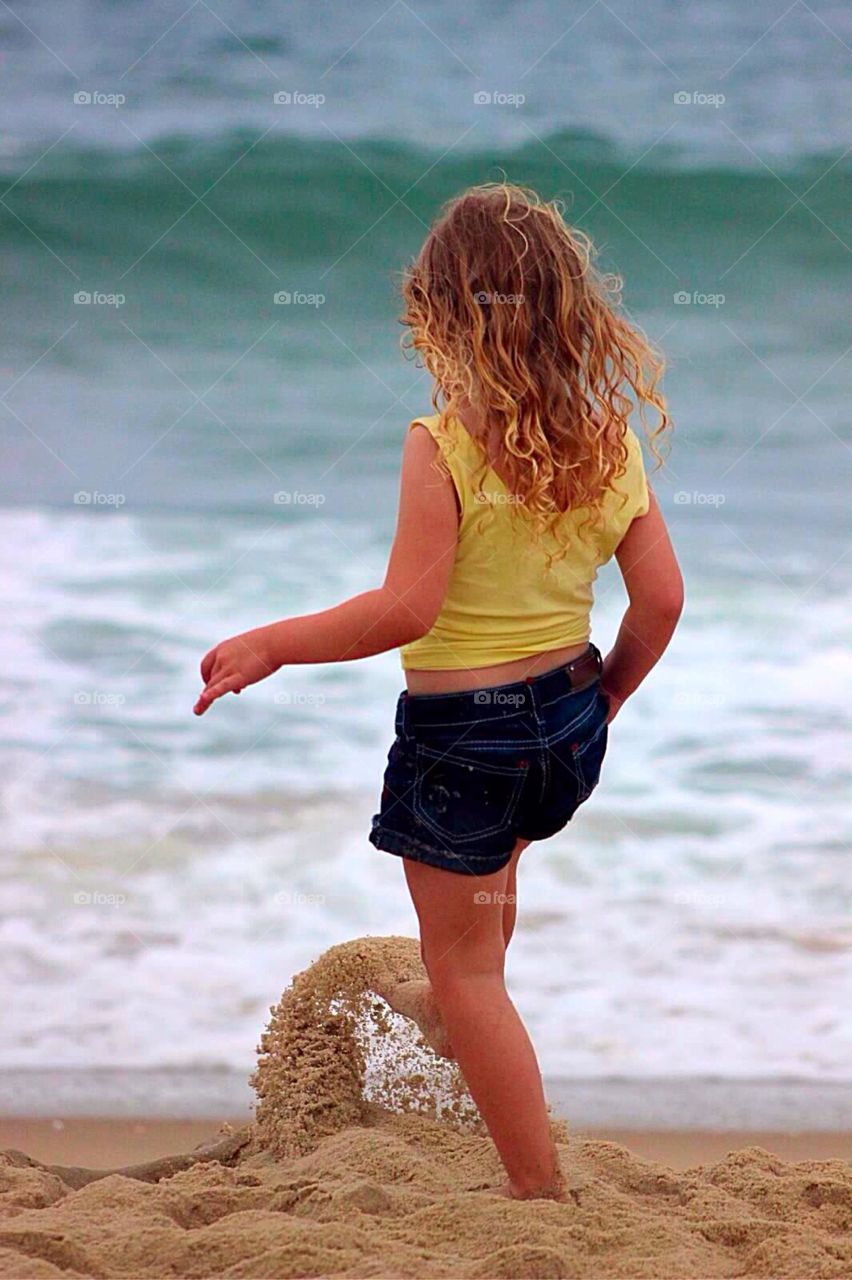 Kicking the Sand. Four year old little girl kicking the sand on the beach. 